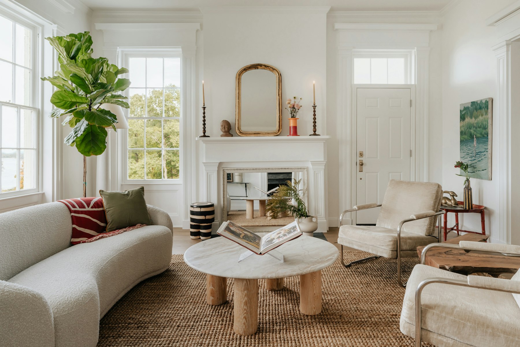 Helles, aufgeräumtes Wohnzimmer mit Sofa, Kamin, rundem Holztisch und großen Fenstern - Quelle: Unsplash (Lizenz: Unsplash License)