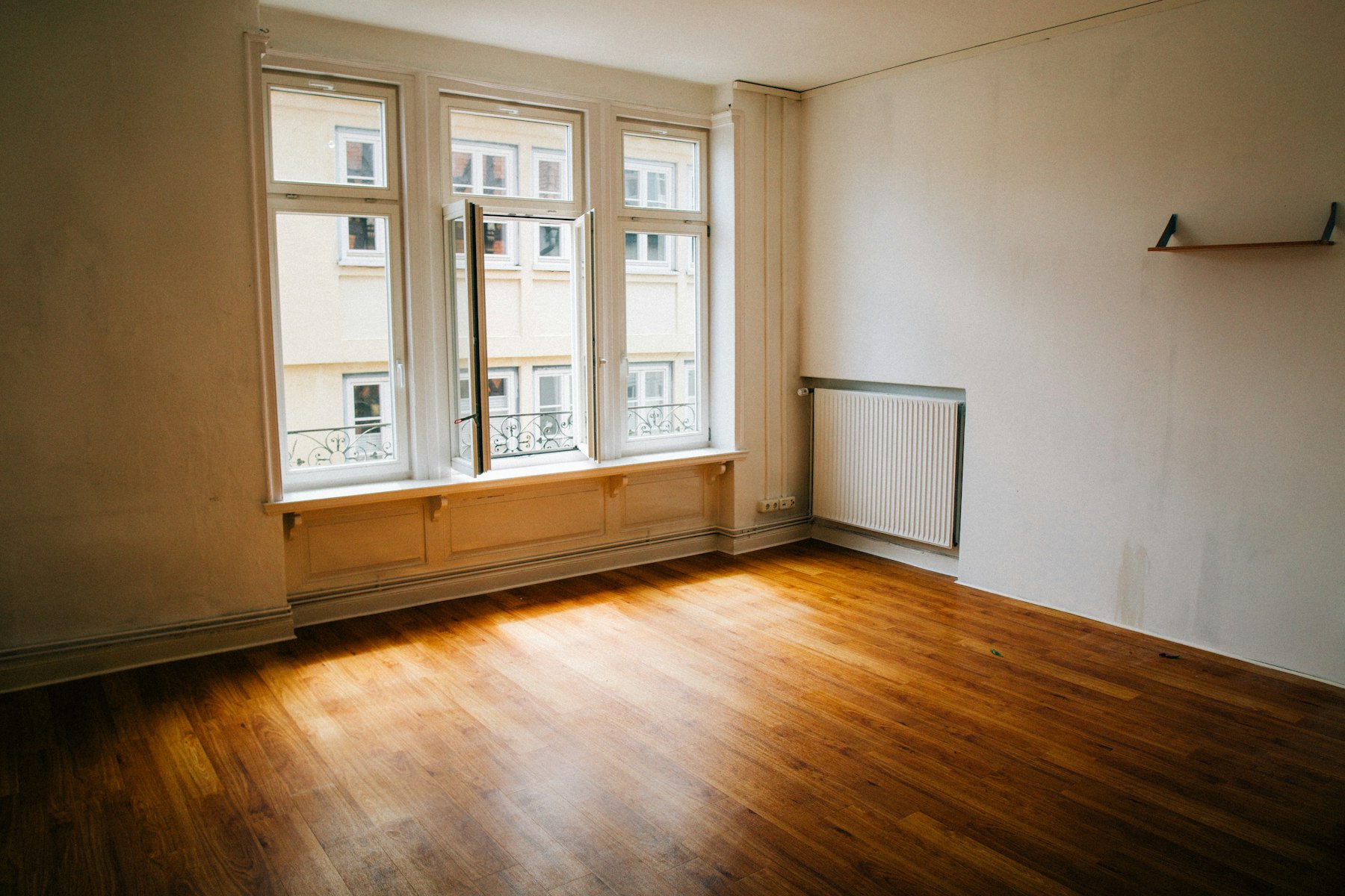 Leerer Altbau-Raum mit Holzdielen, Heizkörper und großen Sprossenfenstern – geräumte Immobilie vor dem Verkauf - Quelle: Unsplash (Lizenz: Unsplash License)