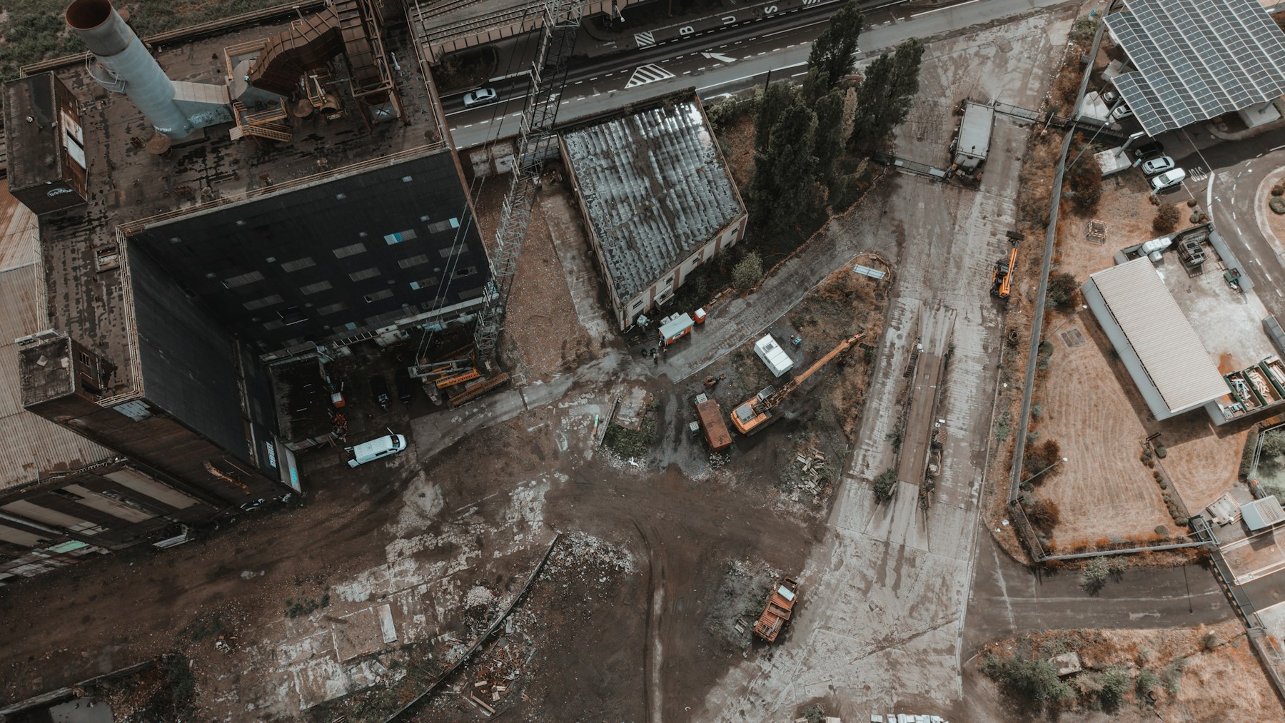 Luftaufnahme einer älteren Industriefläche mit Hallen, Gleisen und Baumaschinen – Altlasten und Baugrund beim Verkauf prüfen - Quelle: Unsplash (Lizenz: Unsplash License)