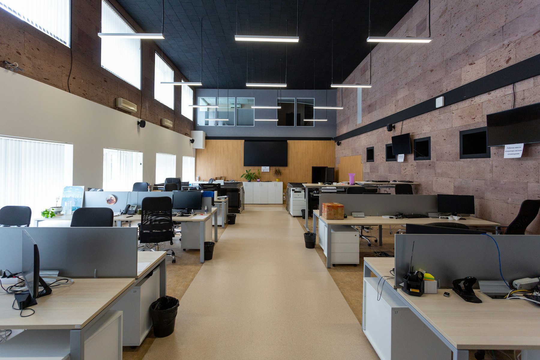 Offene Büroetage mit Schreibtischreihen, Backsteinwand und Lichtbändern – flexible Büroflächen als Kaufkriterium - Quelle: Unsplash (Lizenz: Unsplash License)