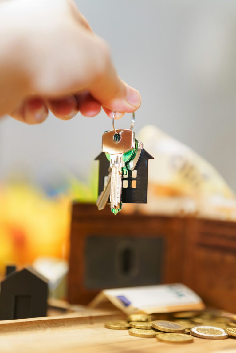 Hand hält Hausschlüssel mit hausförmigem Anhänger – Schlüsselübergabe beim Immobilienverkauf