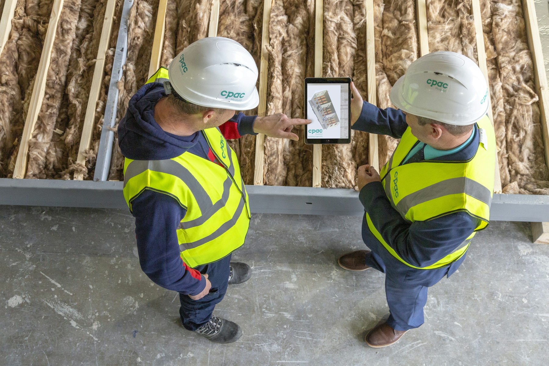 Zwei Fachleute mit Schutzhelm prüfen auf einer Baustelle Pläne auf einem Tablet – Umnutzung einer Gewerbeimmobilie technisch prüfen - Quelle: Unsplash (Lizenz: Unsplash License)
