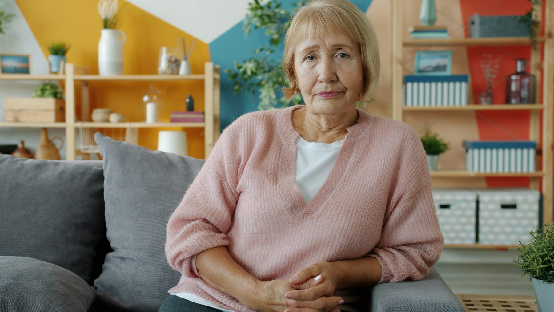 Ältere Frau sitzt entspannt auf dem Sofa im eigenen Wohnzimmer – wohnen bleiben mit Nießbrauch - Quelle: Unsplash (Lizenz: Unsplash License)